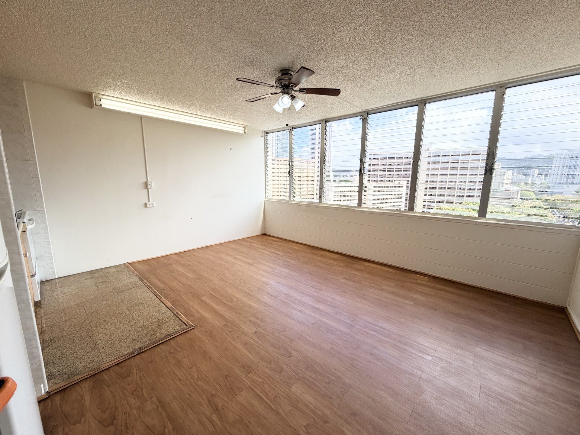 A room with a ceiling fan and wooden flooring.